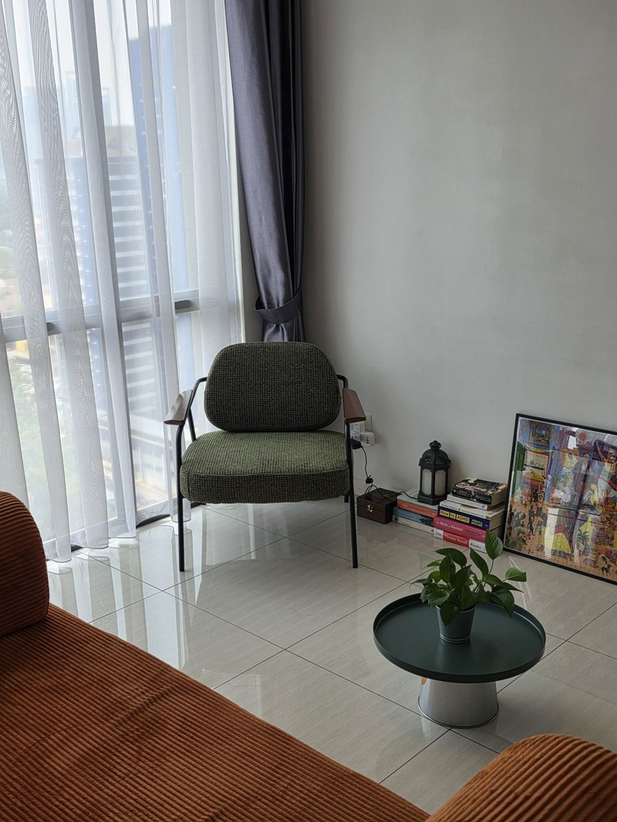 Seating corner with an armchair, plant, and a stack of books used in sessions